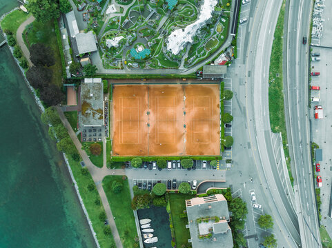 Aerial view of people playing tennis in a tennis club court along Lugano lake, Melide, Ticino, Switzerland.