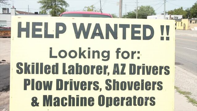 help wanted looking for skilled laborer az drivers plow drivers shovelers and machine operators sign with person running by in background, yellow sign with black writing