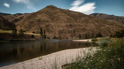 Wide angle long exposure view of little Salmon river on rocky beach with mountain views in Riggins Idaho