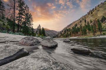 Wide angle long exposure view of little Salmon river on rocky beach with mountain views in Riggins Idaho