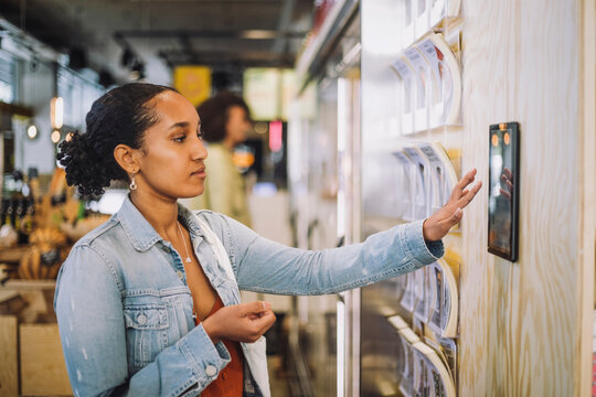 Female customer using digital tablet mounted on wall at grocery store