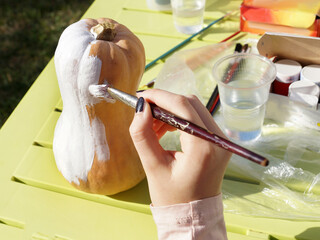 Halloween, a woman's hand paints a pumpkin with paints