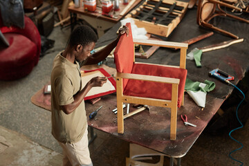 High angle portrait of young black man restoring old furniture in carpentry workshop, copy space