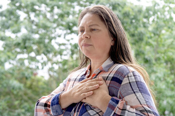 excitedly woman 40 years old in plaid shirt holds to heart, sudden chest pain, closeup face with...