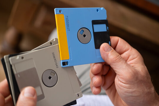 Elderly male hand holding vintage electronic data storage devices Collection from 80s, 90s, disk, flash drives, Nostalgia for Technology, rapid advancements from flash drives to modern storage methods