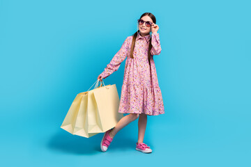 Full body photo of little young schoolgirl kid holding bags fashion discount look mockup sunny weather isolated on blue color background