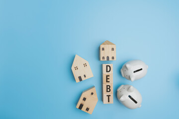 Financial, Accounting, banking, investment, saving money concept. Top view, Flat lay DEBT on wood of cube with 2 piggy banks, and little wood house on blue background with copy space.