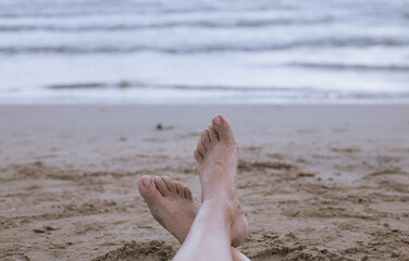 Vacation. Woman legs closeup girl relaxing on the beach enjoying the sun