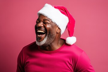 Dark-skinned man wearing a Santa Claus hat on a red background.