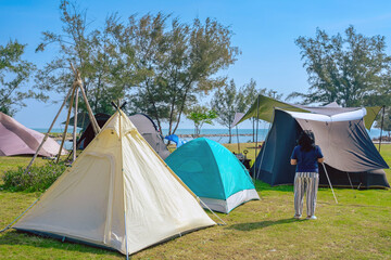 Camping tent and activity on field near the beach. Tent camping area for tourists on lawn near the beach. Holiday outdoor activities with travel and camping at seaside. Happiness outdoor recreation.