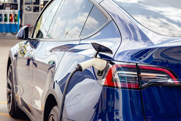 Charging electric vehicle with cable EV plugging in cable while charging electric car. EV charging...