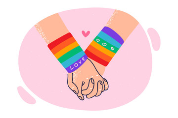 Hands of LGBT lovers in rainbow bracelets, for concept problems tolerance towards gays and lesbians
