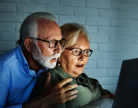 television watching couple laptop night home evening horror scared elderly senior mature active old scary computer tv fear shock woman man movie entertainment fun emotion thriller