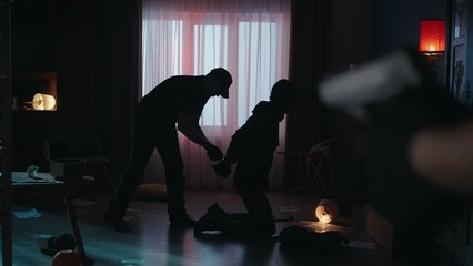 The arrest of the robber in a dark apartment, lit with red light. Side view of a criminal kneeling...