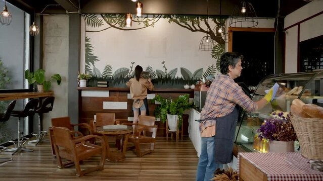 Elderly Asian mothers, with daughter owns this cafe bakery where two them stand, two help clean up cafe after closing, after lot people use service during day, be ready open shop tomorrow.