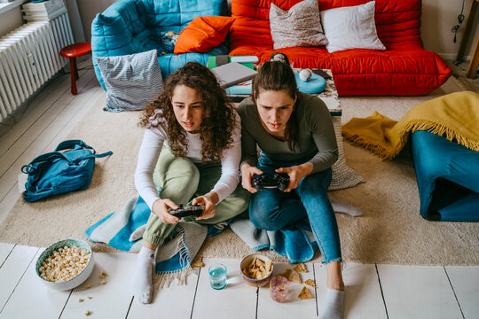 Young female friends playing video game in living room at home