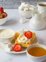 Breakfast Belgian waffles with cream cheese, strawberries, honey with tea and marshmallows.