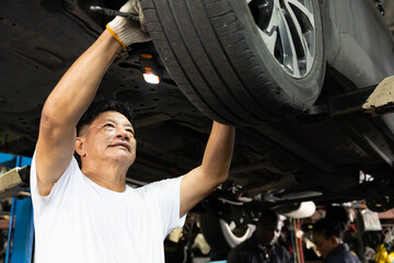 mechanic checking and fixing tire at underneath the car