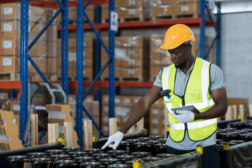 African American male warehouse worker wearing safety uniform using digital tablet inspecting...
