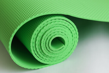 A green yoga mat isolated on a white background. Сoncept of fitness equipment.