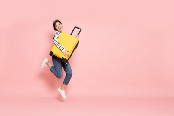 Asian happy woman jumping with yellow suitcase isolated on pink background, Tourist girl having...