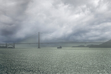 San Francisco, CA, USA - July 13, 2023: Heavy gray storm clouds over Golden Gate Bridge with light...