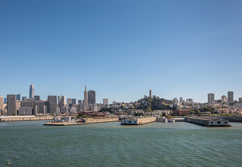 Obraz premium San Francisco, CA, USA - July 13, 2023: Several docks in front of financial district and downtown cityscape under blue sky with Coit tower in center