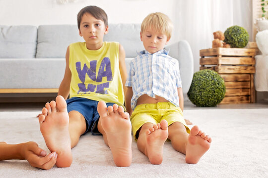 Happy positive children, tickling on the feet, having fun together, boy brothers at home having wonderful day of joy