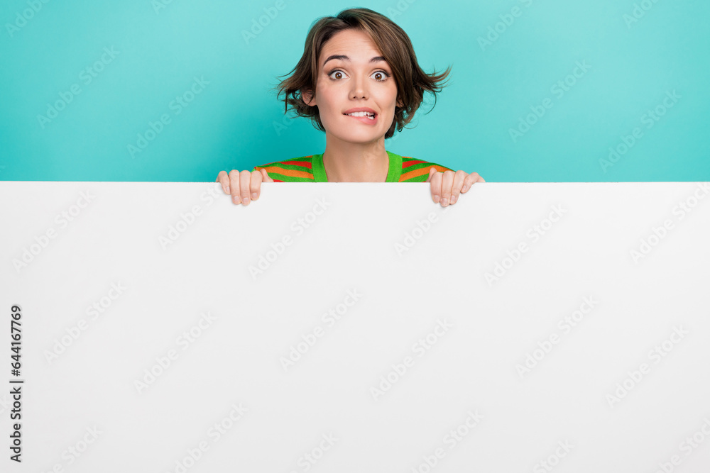 Sticker Portrait of nice cheerful person biting lips behind empty space novelty billboard isolated on turquoise color background