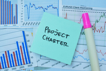 Concept of Project Charter write on sticky notes isolated on Wooden Table.