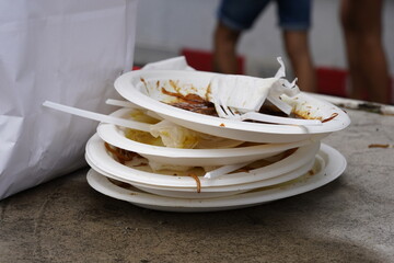 White plastic plates are stacked on one another. There are rests of the food on the  plates as well...