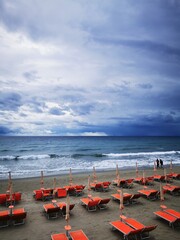 Photo of a vibrant beach scene with a group of orange chairs overlooking the ocean