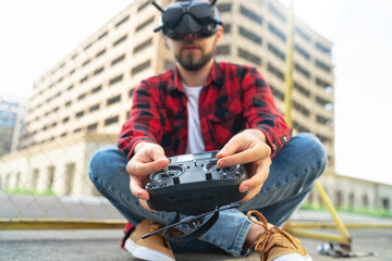 Outdoor portrait of casually dressed male fpv pilot operating multicopter drone using goggles nad...