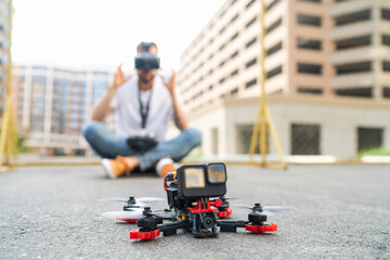 Outdoor shot of fpv multicopter drone pilot taking off goggles after landing the copter
