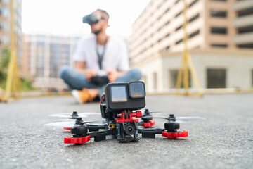 Street photo of fpv multicopter drone landing on the street road with the male pilot operating on the background - 644174577