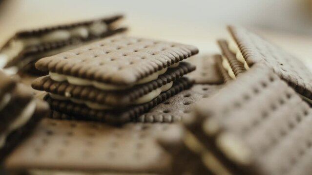 Triple chocolate biscuits with white filling are rotated on a turntable. Close-up.