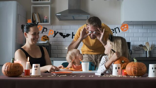 Family of four having fun while preparing for Halloween party in the kitchen, slow motion