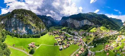 Poster Switzerland travel . most scenic places. beautiful Lauterbrunnen village aerial drone view of  valley surrounded by impressive Alps mountains and waterfalls © Freesurf