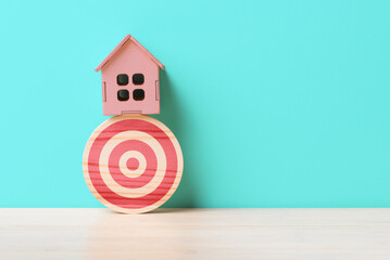 House model on wooden target over blue background with copy space. Concept of purpose in acquiring homes and real estate - 644185947