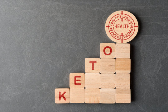 Stage made of wooden blocks with letters Keto and target with words weight loss and increased energy. Concept of ketogenic diet