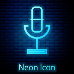 Glowing neon Microphone icon isolated on brick wall background. On air radio mic microphone. Speaker sign. Vector