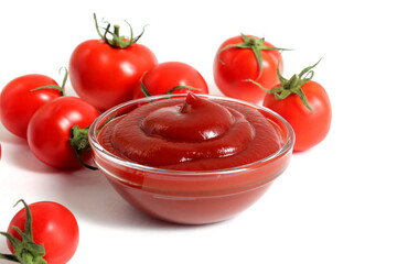 On a white background there is a plate with ketchup and tomatoes.