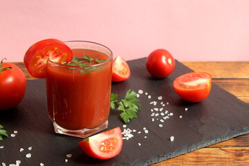 There is one glass of tomato juice on a stone board.	