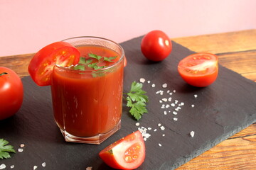 There is one glass of tomato juice on a stone board.