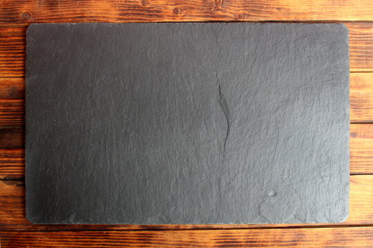 There is a black stone board on a wooden table.