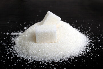 White scattered sugar with refined sugar lie on a black background.