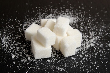 Refined sugar in a pile lies on a black background.