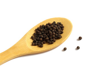 On a white background lies a wooden spoon with seasoning black peppercorns.