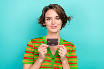 Photo of adorable cheerful woman dressed striped t-shirt smiling holding credit card isolated turquoise color background