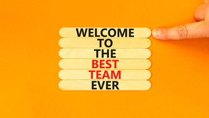 Welcome to best team symbol. Concept words Welcome to the best team ever on wooden stick on beautiful orange background. Businessman hand. Business, motivational and welcome to best team concept. - obrazy, fototapety, plakaty